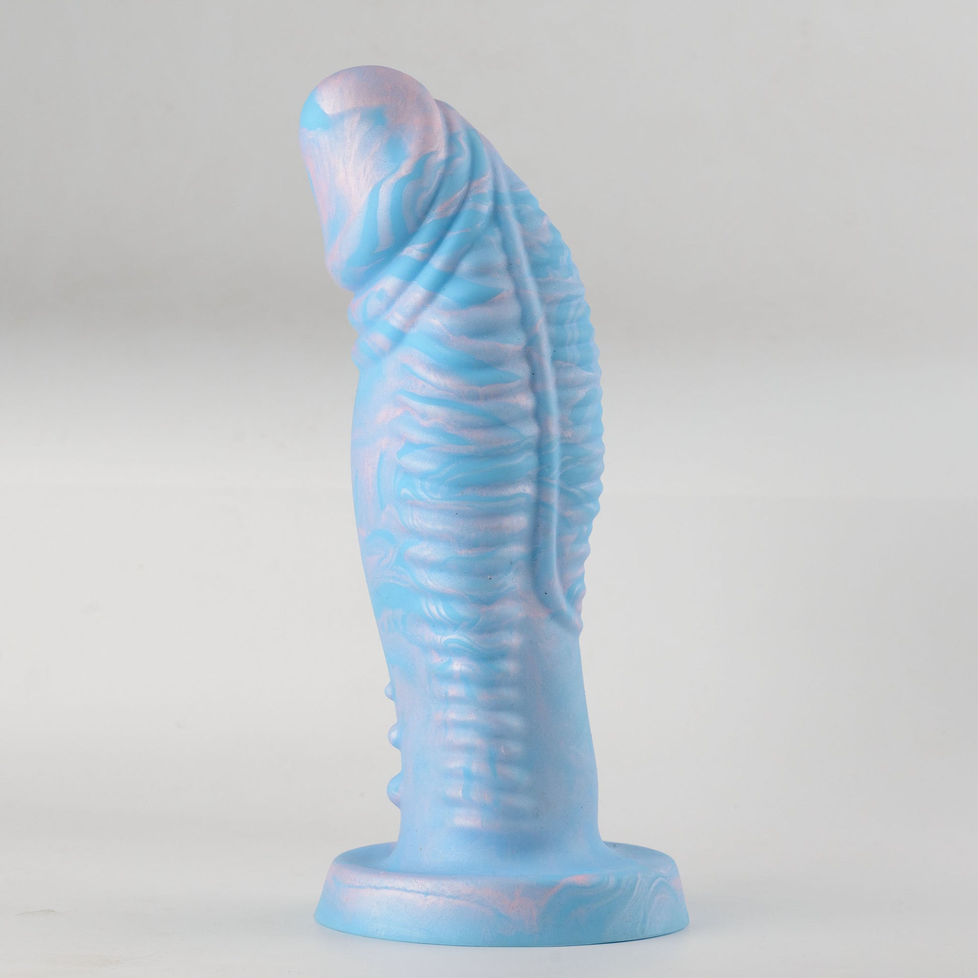 Leviathan Fantasy Collection silicone dildo - low-angle side view standing on flat round base showing strong forward curve, sky blue and pink-purple marble swirl colorway with fantasy forked tip drooping forward, dense horizontal rib ring texture along full shaft and vertical ridge running along shaft underside - no-scrotum design - body-safe platinum-cured single-density silicone | RealTouch Lab
