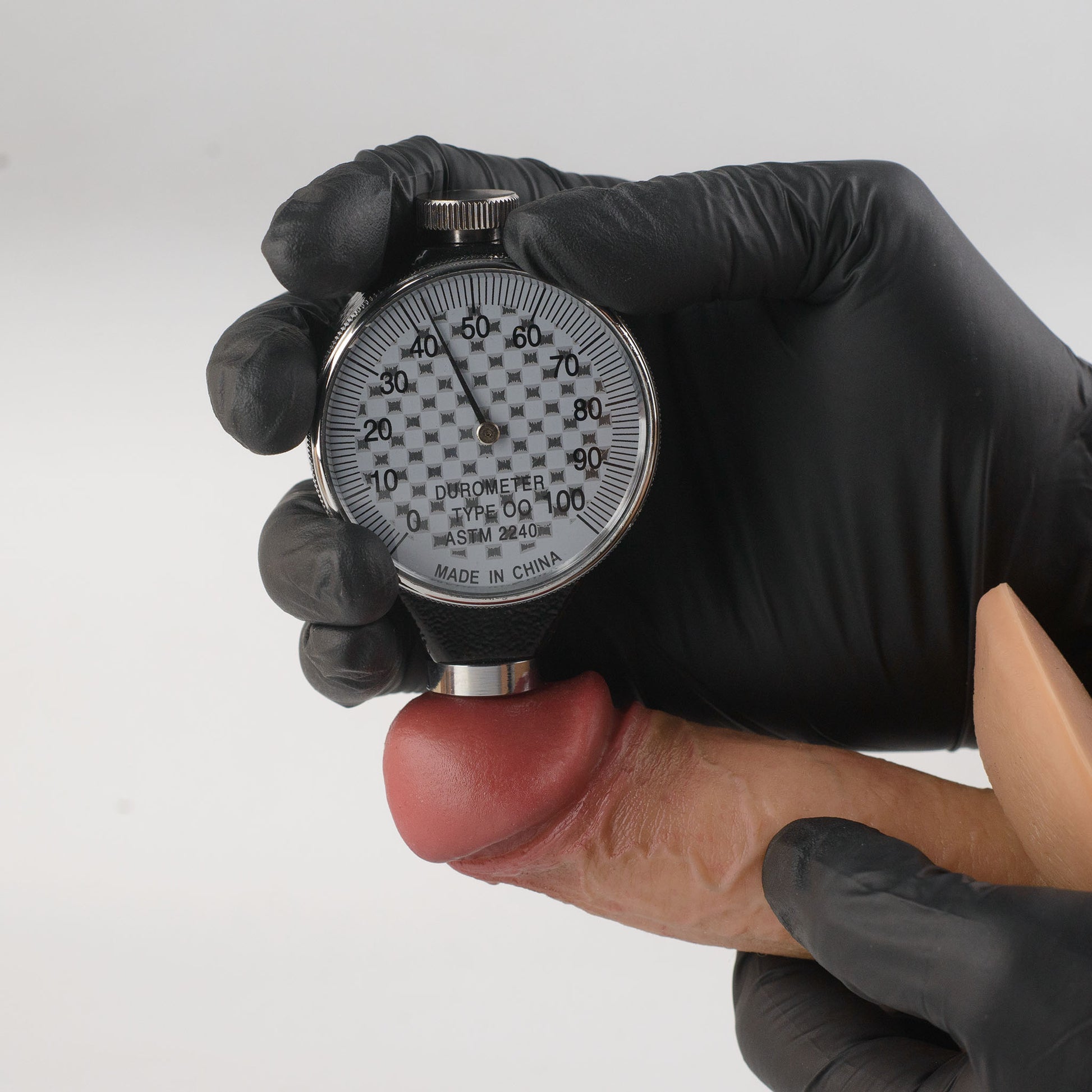 Stage 04 Ossifying Dragon hand-painted silicone dildo - Shore 00 durometer (ASTM 2240) hardness test on glans showing approximately 45 Shore 00 softness rating - scientifically verified ultra-soft outer layer - dual-density body-safe platinum-cured | RealTouch Lab
