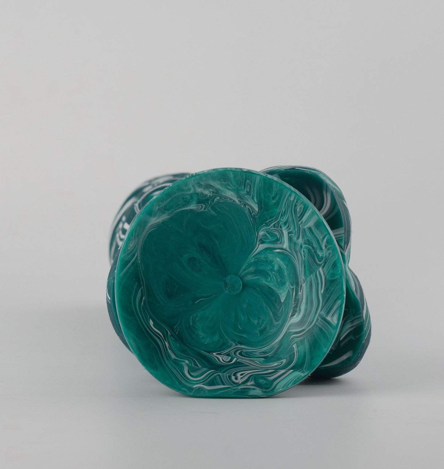 Griffin Fantasy Collection silicone dildo - bottom view lying flat showing teal marble swirl suction cup cavity with smooth concave surface and organic scalloped edge detail around base perimeter - 2.95in/7.5cm diameter suction cup for strong hands-free surface adhesion - body-safe platinum-cured single-density silicone | RealTouch Lab
