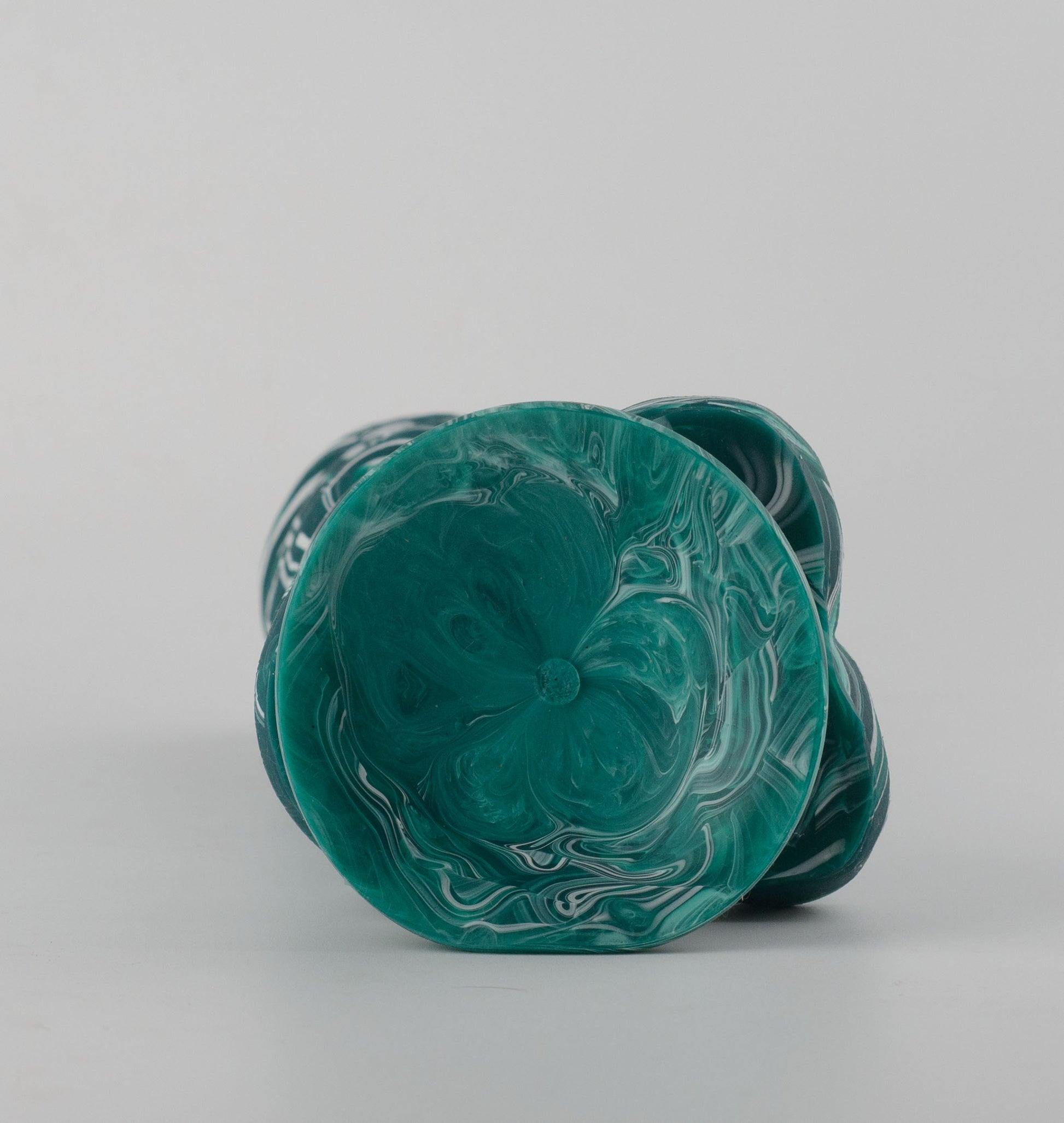Griffin Fantasy Collection silicone dildo - bottom view lying flat showing teal marble swirl suction cup cavity with smooth concave surface and organic scalloped edge detail around base perimeter - 2.95in/7.5cm diameter suction cup for strong hands-free surface adhesion - body-safe platinum-cured single-density silicone | RealTouch Lab
