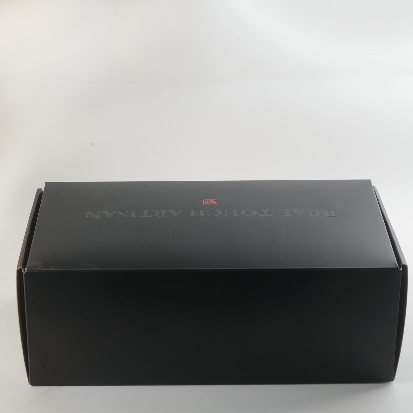 Leviathan Fantasy Collection silicone dildo - discreet matte black shipping mailer box with subtle REAL TOUCH ARTISAN branding and small red seal logo on top, no product description or category information on exterior for complete privacy - shipped in plain discreet packaging | RealTouch Lab
